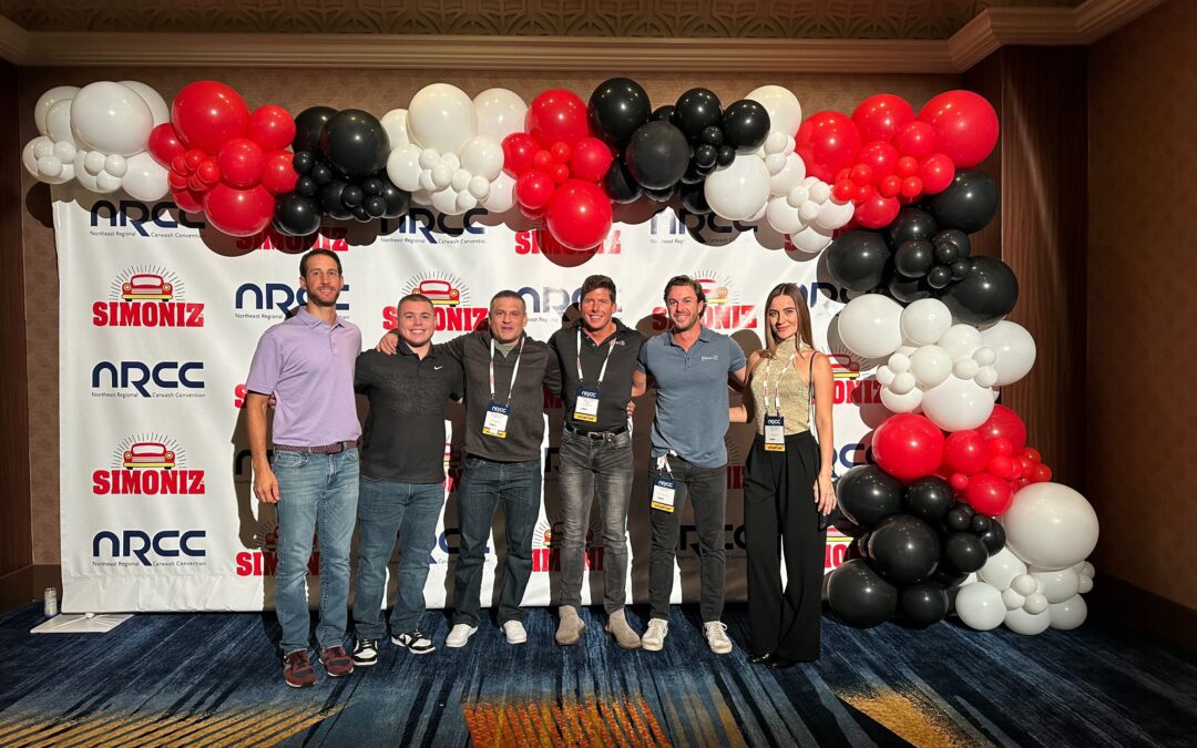 The Miracle team poses together at the Northeast Regional Carwash Convention (NRCC) 2024 in Atlantic City, showcasing professionalism. Everyone is smiling, dressed in cocktail attire, and surrounded by the convention backdrop.